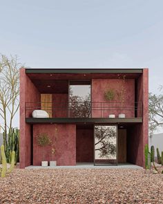 a house with red walls and plants on the outside, surrounded by cacti