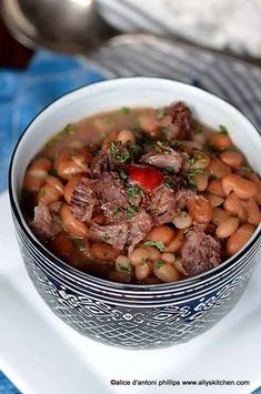 a bowl filled with meat and beans on top of a white plate