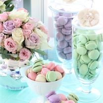 a table topped with vases filled with flowers and macaroons