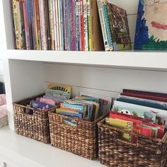 the books are in baskets on the shelf next to the bookshelf full of children's books