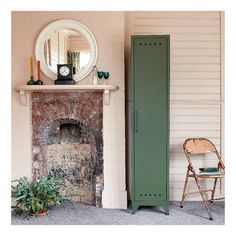 a tall green locker sitting next to a brick fire place in a room with a mirror on the wall