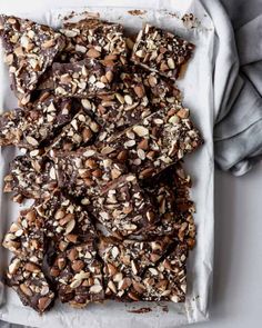 a tray filled with chocolate and nuts on top of a white table cloth next to a napkin