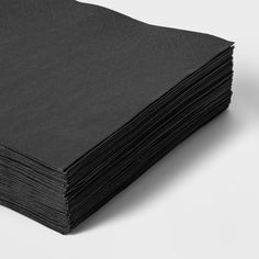 a stack of black napkins sitting on top of a white table next to each other