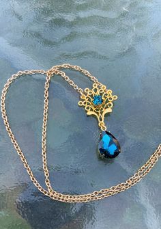 This is one of the beautiful necklaces that Kate wears in Bridgerton 2. It reminds me of a peacock with the shape and teal blue colors. It is made with a gold tone filigree that has a teal blue rhinestone set into the center. Another teal blue drop rhinestone hangs from the bottom. Choose your preferred length, as shown it is 16 inches. This lovely piece makes a great gift for a loved one or yourself. Elegant Peacock Color Pendant Jewelry, Elegant Peacock Design Necklace For Gift, Elegant Peacock Pendant Necklace, Elegant Peacock Color Pendant Necklace, Elegant Gold Necklace With Peacock Design, Victorian Turquoise Necklace For Wedding, Formal Gold Necklace With Peacock Design, Ornate Peacock Design Necklace For Gift, Elegant Blue Peacock Design Jewelry