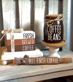 two coffee mugs sitting on top of a table next to some books and a wooden spoon