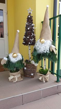 three gnomes are sitting next to each other in front of a christmas tree and potted plant