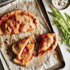 two chicken calzones sitting on top of a sheet of parchment next to green beans