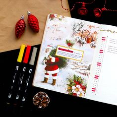 an open christmas planner with santa clause on it next to some crayon markers