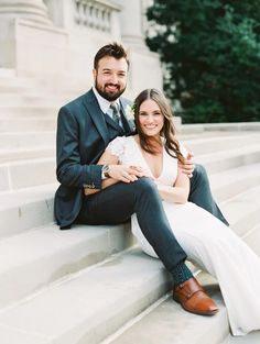 a man and woman are sitting on the steps posing for their wedding photo in front of some stairs