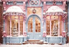 a pink and blue building with christmas decorations on the front door is covered in snow