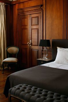 a bedroom with wood paneled walls and white bedding