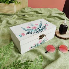 a white box sitting on top of a bed next to sunglasses