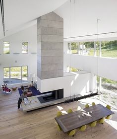 an open living room and dining area in a modern house with white walls, wood flooring and large windows