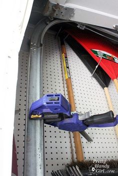 some tools are hanging on the wall next to each other in a storage area with pegs