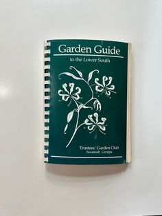 the garden guide to the lower south sits on a white surface next to an open notebook