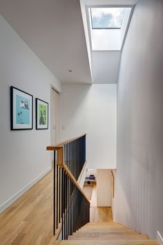 the stairs are made of wood and have black railings on each side, with skylights above them