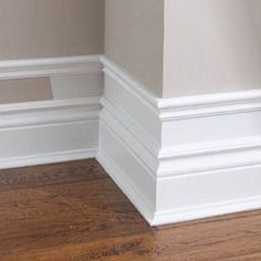 the corner of an empty room with wood flooring