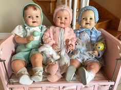 three baby dolls are sitting on a pink bench