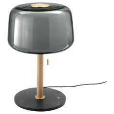 a gray table lamp with a wooden base and a black shade on the top, sitting on a white surface