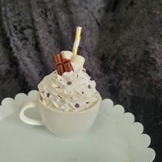 a white cup filled with whipped cream and chocolate pieces on top of it's saucer