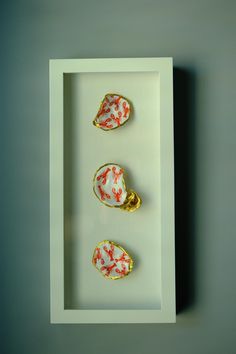 three pieces of art on display in a white frame with gold trim and red designs