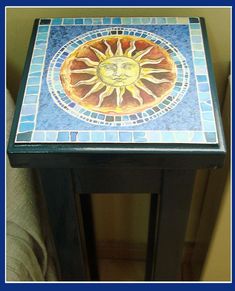 a small end table with a sun design on the top and blue tiles around it