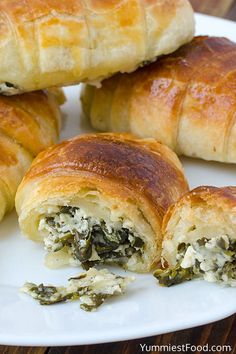 several croissants filled with spinach and cheese on a white platter