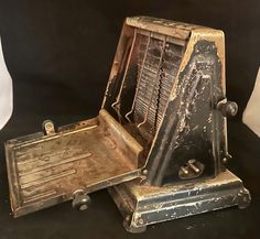 an old metal machine sitting on top of a black table next to a white pillow