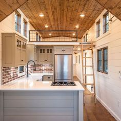 a kitchen with a stove top oven sitting under a wooden ceiling next to a ladder