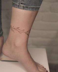 a woman's foot with a small flower tattoo on her left ankle and right leg