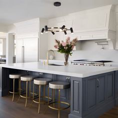 a kitchen island with stools in front of it and flowers on the countertop