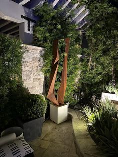 an outdoor area with trees and plants in the background at night, including a sculpture