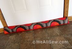 an orange and black pillow sitting on the floor in front of a door with a wooden frame