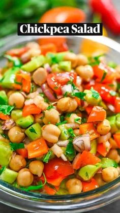 a glass bowl filled with lots of veggies and chickpeas in it