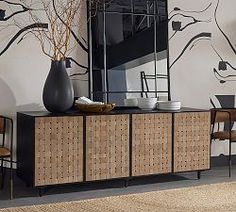 a black vase sitting on top of a wooden cabinet in front of a wall mural