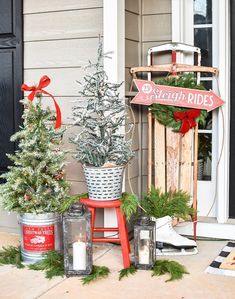 christmas decorations on the front steps of a house with red ribbon and evergreens in buckets