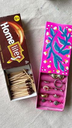 an open box with matches and rings in it on the floor next to a package of matches