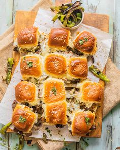 a wooden cutting board topped with rolls covered in cheese