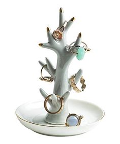 a white tree with rings on it sitting in a bowl next to a ring holder