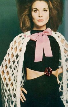 a woman in a black dress and white shawl with a pink bow on her head