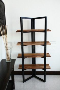 a room with a wooden shelf next to a black table and white wall behind it