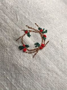 a close up of a piece of cloth with embroidery on it and some red berries