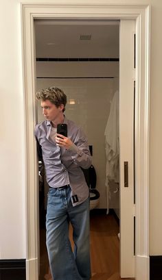 a man is taking a selfie with his cell phone in the mirror while wearing jeans