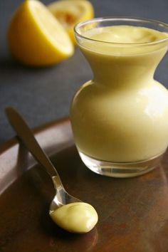 a spoon sitting on top of a wooden table next to a glass vase filled with liquid