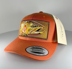 This Cutthroat Trout patch adorns a 6 panel rustic orange snapback trucker style mesh Yupoong classic hat with a khaki mesh back. I hope this becomes your next lucky fishing "must have" item :) Artwork created specifically to be a 100% embroidered iron on patch measuring 5"x2.5". This patch is carefully ironed onto the hat and then sewn with 130lb thread so this fish won't get away.   **Since these hats were handmade the sewing may not be perfect, but I believe it gives each hat some character, Adjustable Orange Trucker Hat With Flat Bill, Orange Curved Brim Trucker Hat For Outdoor, Adjustable Orange Hat With Curved Bill, Orange Adjustable Trucker Hat With Curved Bill, Adjustable Orange Snapback Hat For Outdoor, Orange Curved Brim Trucker Hat, Orange Snapback Hat For Outdoor, Adjustable Orange Trucker Hat, Orange Trucker Hat, One Size Fits Most