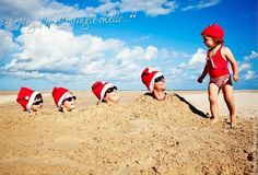 a group of children wearing santa hats on top of a sandy beach