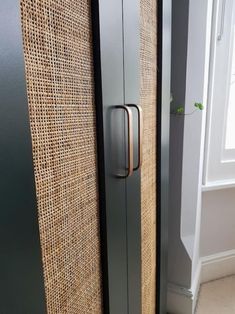 a tall metal cabinet next to a window with burlap coverings on it