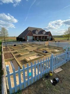 a large yard with several raised beds in the middle and a white picket fence surrounding it