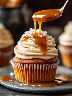 a cupcake with caramel sauce being drizzled over it and topped with frosting