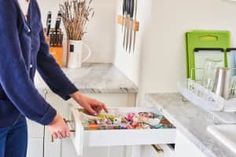 a man standing in front of a kitchen counter with an open drawer